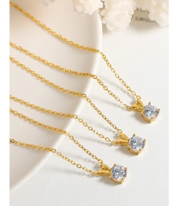 Macro shot of three minimalist gold titanium necklaces featuring claw-set zircon pendants