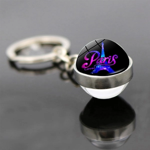 Detailed macro view of Eiffel Tower glass pendant keychain with blue galaxy background
