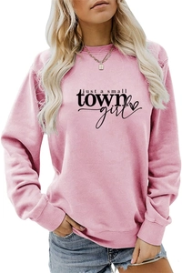 Close-up of 'just a small town girl' black print on pink crewneck cotton sweatshirt