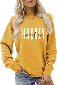 Detail of the white HOCKEY wife letter print on a mustard yellow crewneck sweatshirt