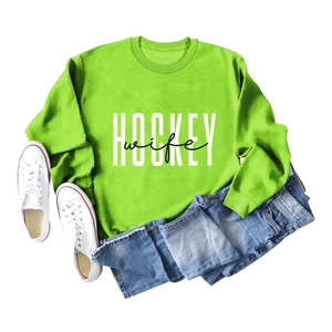 Flat lay of bright green crewneck sweatshirt with Hockey Wife print and denim jeans