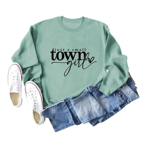 Flat lay of mint green crewneck sweatshirt with just a small town girl print and denim