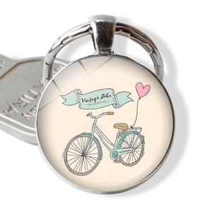 Macro detail of vintage blue bicycle and pink balloons under a glass dome keychain