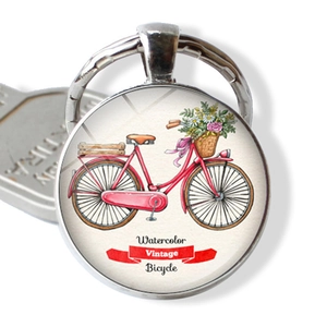 Macro detail of round silver keychain with vintage watercolor red bicycle illustration
