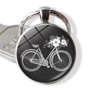 Close-up of vintage bicycle and flower basket art under glass dome on silver keyring