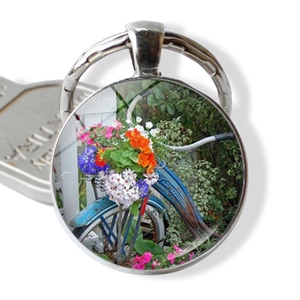 Detail view of round vintage bicycle keychain with glass cabochon floral basket pattern