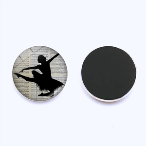 Macro view of round glass magnet showing ballet silhouette on vintage music notes