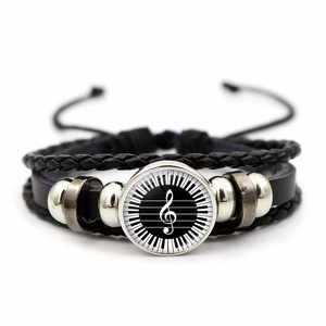 Close-up of leather bracelet featuring piano keys and treble clef glass cabochon