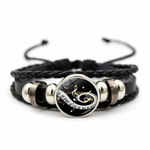 Macro detail of music-themed bracelet with piano keys and notes on glass gem inlay