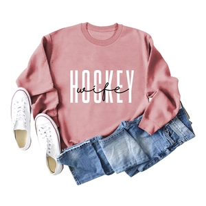 Flat lay of pink hockey wife sweatshirt paired with denim jeans and white sneakers