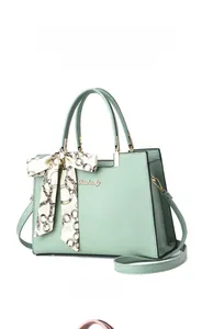 Détail du sac à main vert menthe en cuir grainé avec foulard élégant et logo métallique