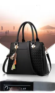 Détail d'un sac à main noir avec des surpiqûres matelassées et un pompon décoratif