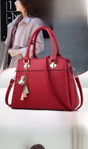 Détail du sac à main bordeaux avec motif en losanges et pendentif à pompons colorés