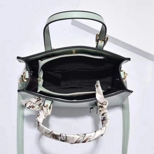 Detail view of mint green handbag interior with three compartments and silk scarf handle