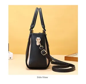 Dettaglio laterale di una borsa a mano bicolore capiente con fibbie metalliche dorate