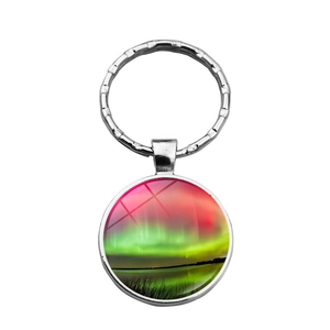 Détail d'un porte-clés rond argenté avec paysage d'aurores boréales sous dôme en verre