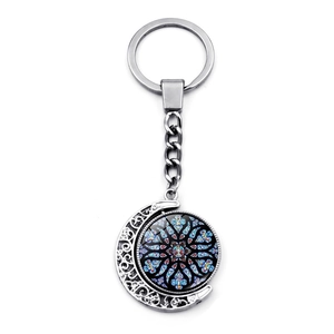 Close-up of rotating moon keychain with colorful stained glass pattern in silver metal