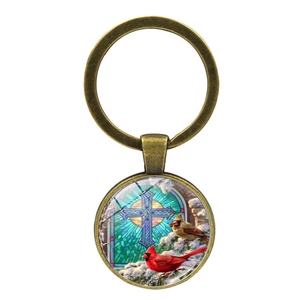 Detail of cardinal bird and cross motif on round glass dome within antique bronze keychain