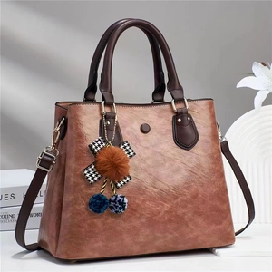 Close-up of vintage brown tote bag with cherry charm and textured faux leather finish