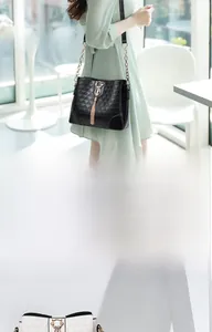 Detail of quilted leather bucket bags in black and white with cat charm and tassels