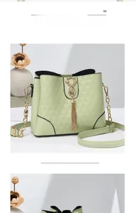 Detail view of mint green bucket bag with embossed triangle pattern and gold cat charm