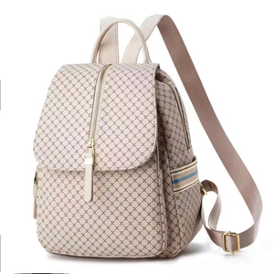 Detail view of beige backpack with brown geometric patterns and vertical zipper pocket