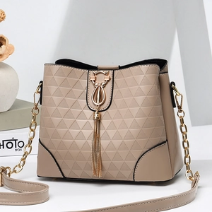 Beige bucket bag with triangle embossing, gold cat clasp, and chain strap in studio setting