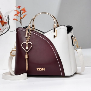 Detail of burgundy and beige patchwork handbag with gold ZZMY logo and heart tassel charm