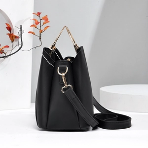 Detail of black leather bucket bag with white stitching and gold triangle handle