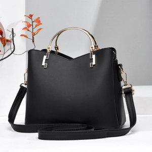 Detail of black leather bucket bag with gold circular handle and adjustable strap