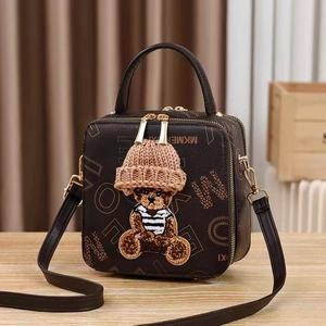 Brown box bag with embroidered bear and monogram pattern on wooden tabletop