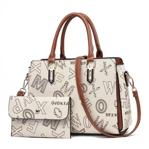 Gros plan du grand sac cabas beige avec des finitions brunes et motifs de lettres