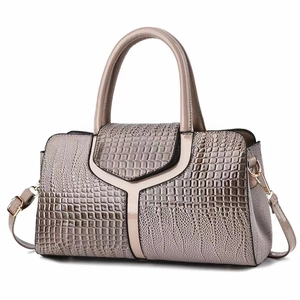 Close-up of champagne crocodile pattern handbag featuring Y-shaped patent leather detail