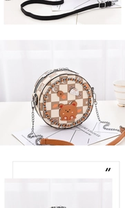 Detail of round crossbody bag with beige checkerboard pattern and cartoon bear patch