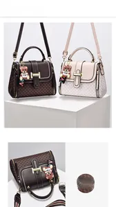 Close-up of monogram leather crossbody bags with gold hardware and bear pendant