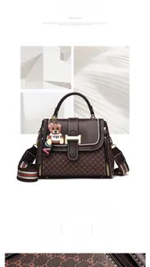 Detail of vintage brown textured crossbody bag with metal buckle and bear charm accessory
