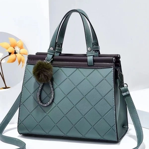 Quilted dark green tote bag with contrast stitching, top handles and a plush ball charm
