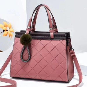 Close-up of pink quilted tote bag with purple trim and green pom-pom charm detail