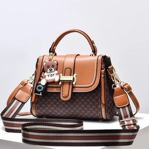 Brown leather handbag with monogram print, striped shoulder strap and teddy bear charm