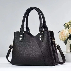 Detail of lychee pattern leather handbag with metallic rivets and shoulder strap