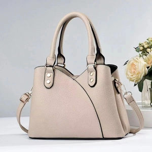 Close-up of beige lychee grain leather tote with curved stitching and silver rivet detail