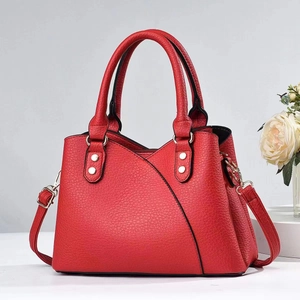 Close-up of red lychee textured leather tote with silver rivets and stitching detail