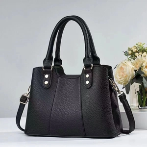 Close-up of black lychee grain leather handbag with elegant gold metal hardware details