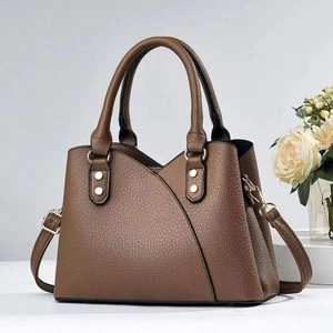 Detail of dark brown lychee leather bag with gold hardware and V-shaped stitching