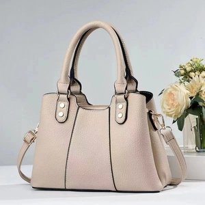 Detail of apricot pebbled leather handbag with gold rivets and adjustable shoulder strap