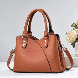Detail of brown litchi texture leather handbag with silver rivets and diagonal stitching