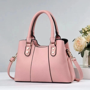 Detail of pink lychee textured faux leather handbag with gold-tone hardware and handles
