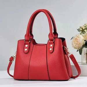 Detailed view of a red lychee grain leather handbag with silver studs and round handles