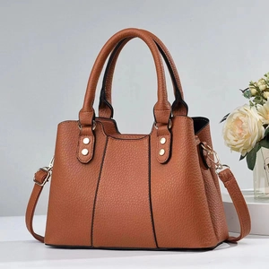 Macro view of caramel brown lychee leather texture and gold metal studs on tote bag