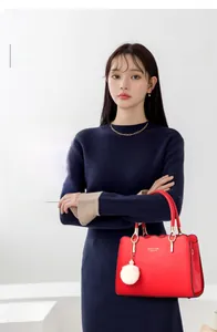 Detail of red leather handbag featuring wavy edge design and gold metal handle connectors